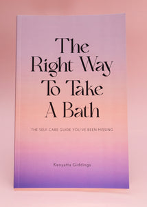 The Right Way To Take A Bath paperback book with a soft touch matte pastel cover against a pink background. The Right Way To Take A Bath is a self-care guide that captures bubble bath tips in a decor-friendly book that makes the perfect spa gift.