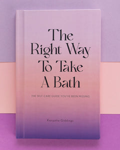 The Right Way To Take A Bath hardcover book with a soft touch matte pastel cover against a pastel gradient background. The Right Way To Take A Bath is a self-care guide that captures bubble bath tips in a decor-friendly book that makes the perfect spa gift.