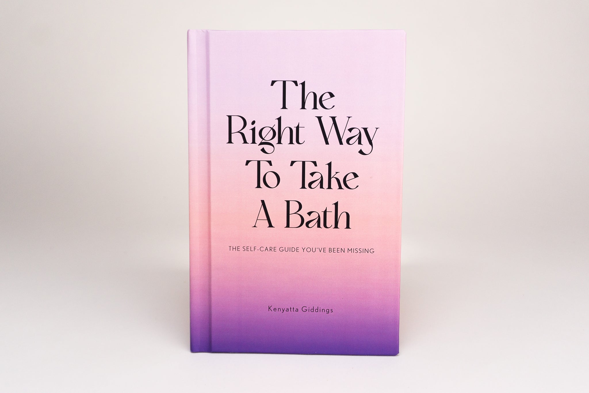 The Right Way To Take A Bath hardcover book with a soft touch matte pastel cover against a white background. The Right Way To Take A Bath is a self-care guide that captures bubble bath tips in a decor-friendly book that makes the perfect spa gift.